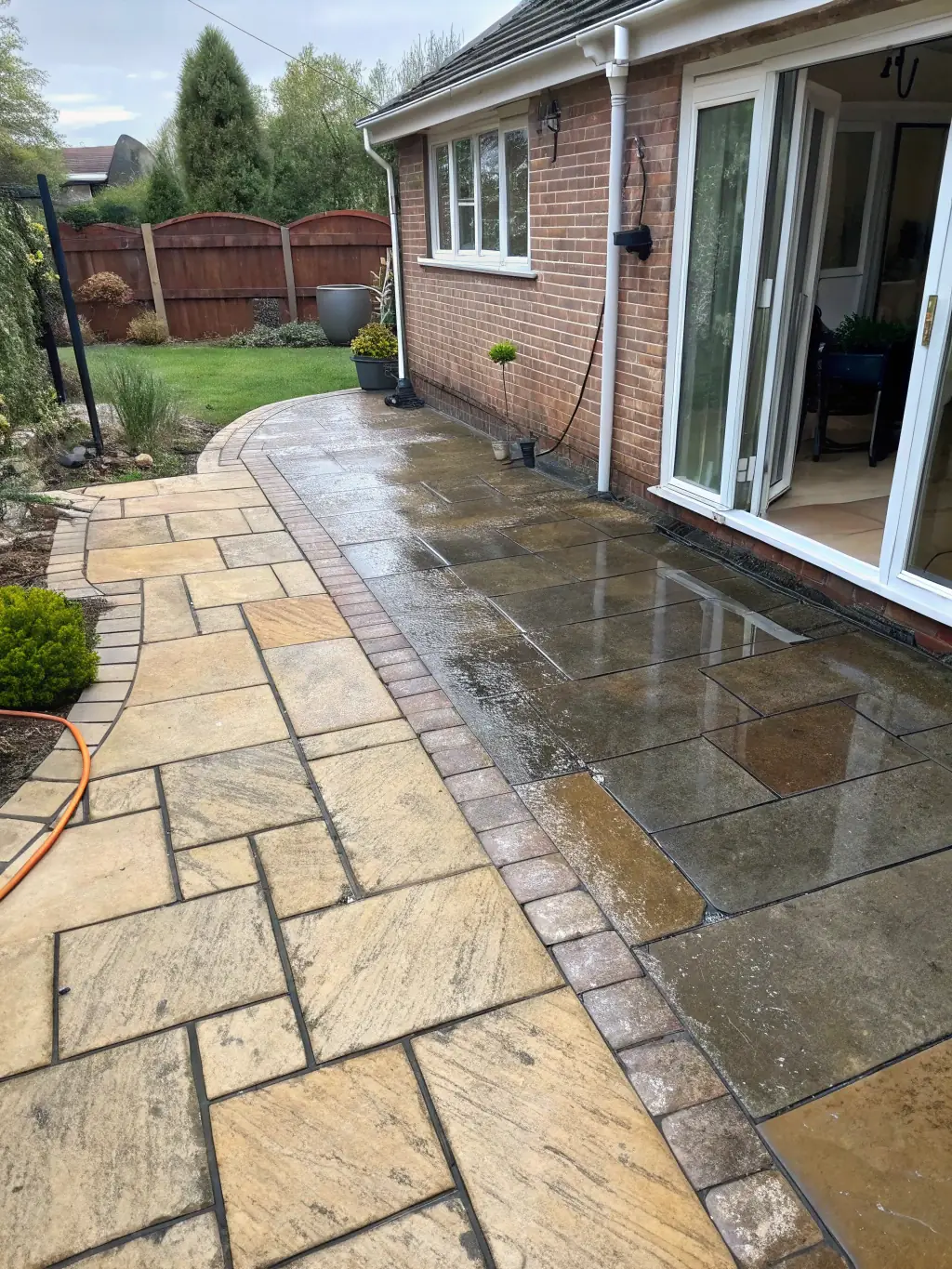 A before-and-after shot of a dirty patio being cleaned with power washing, showing the dramatic transformation.